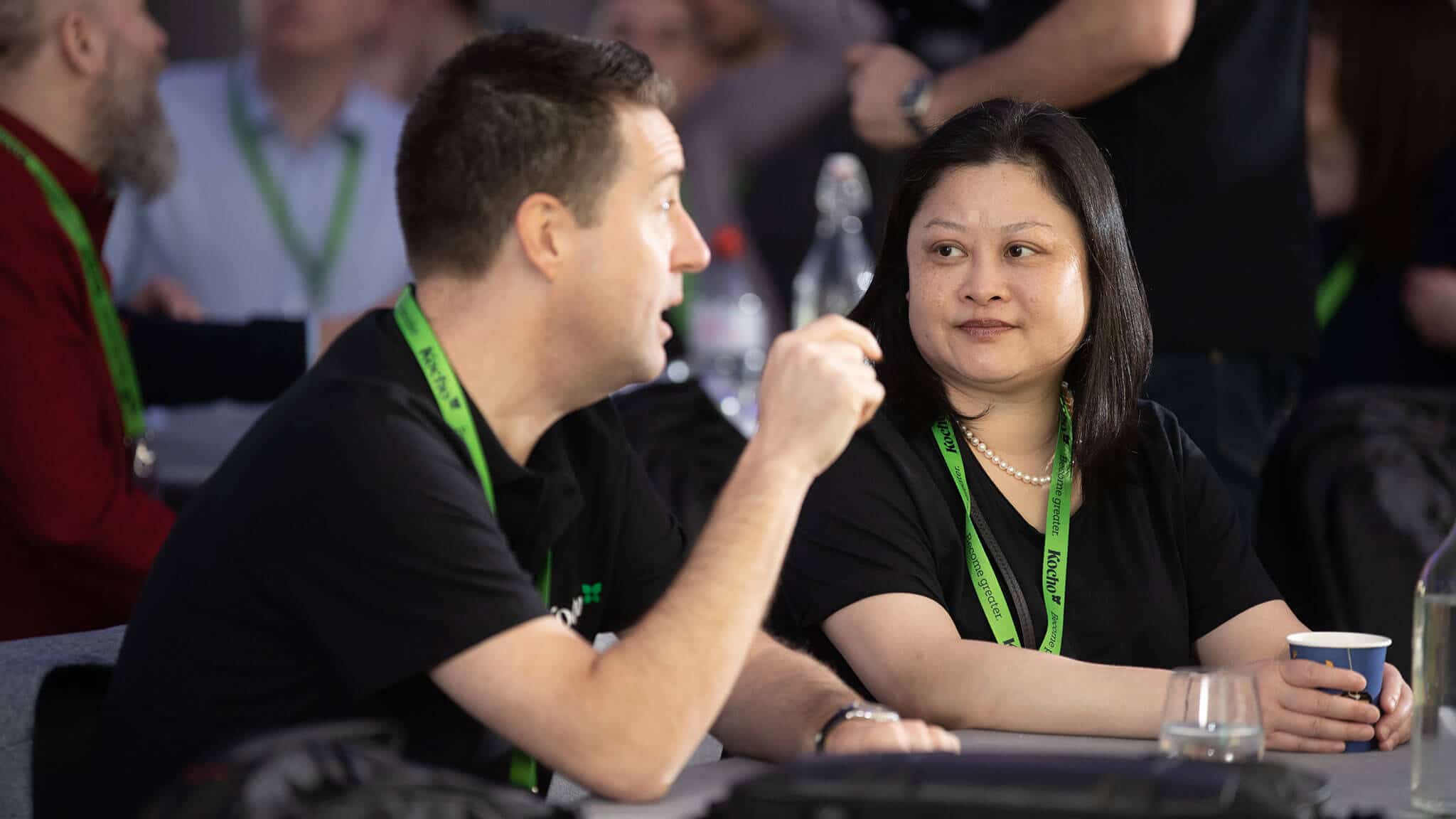 Woman sat at table looking at man gesturing