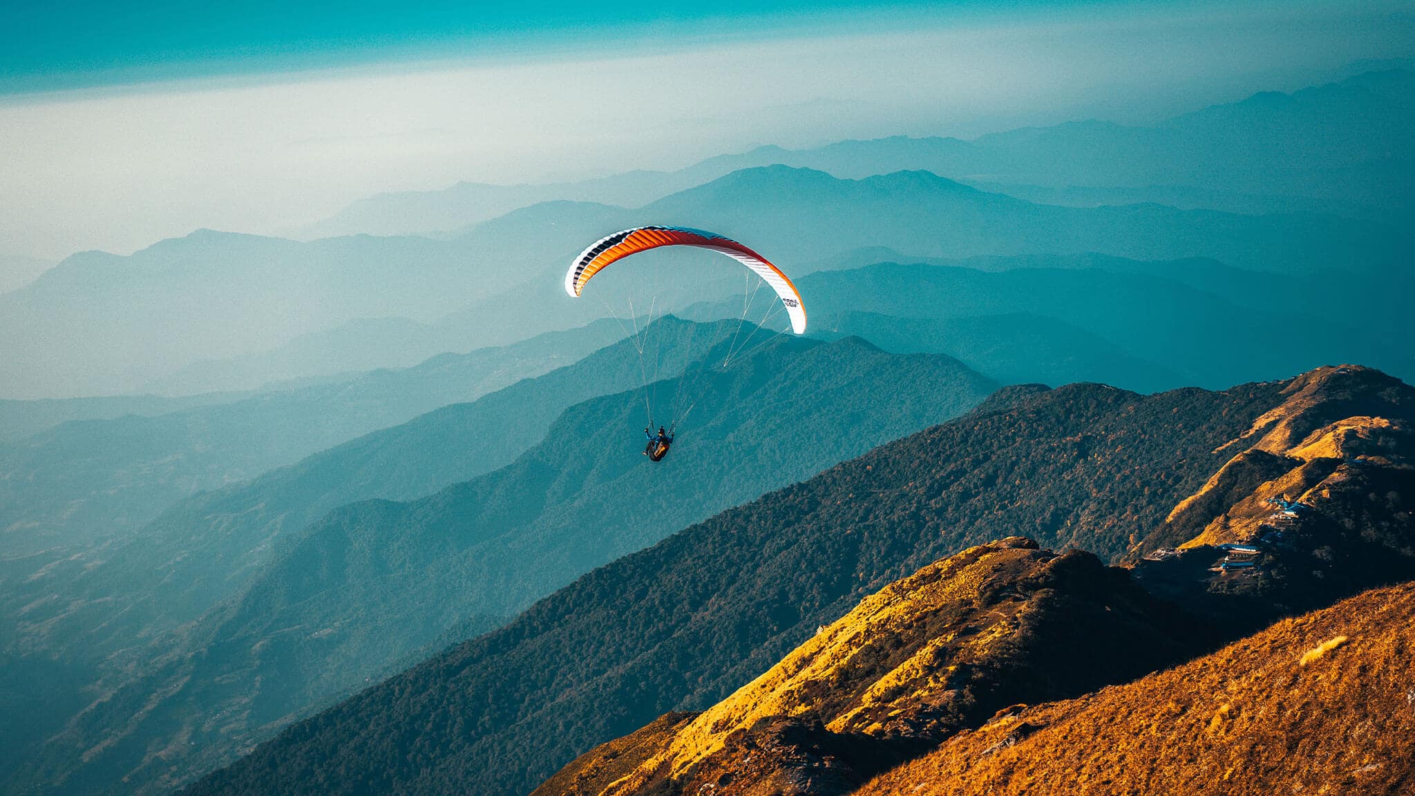 Wide angle shot of paraglider over forested mountains
