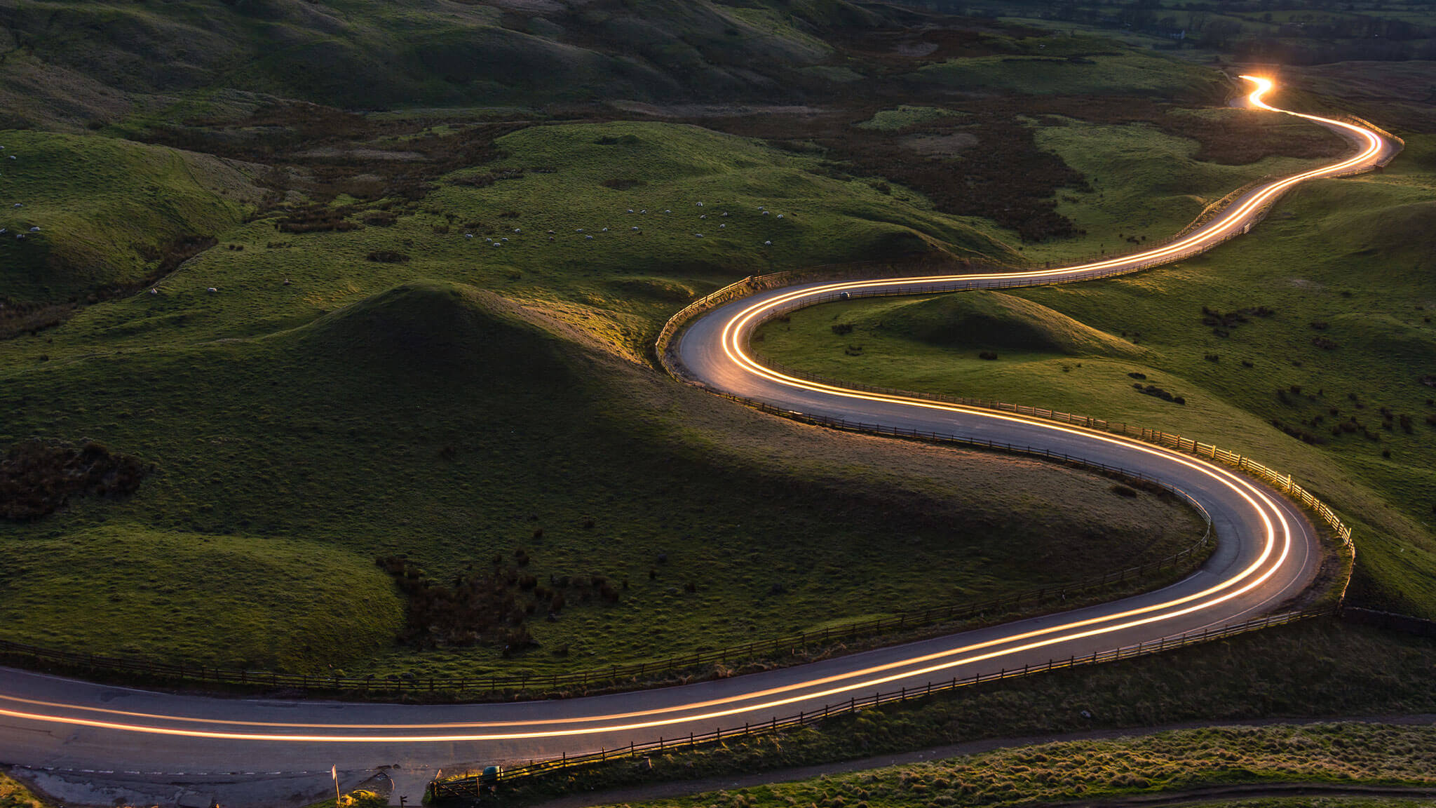 Time lapse of road winding through hills at sunset.