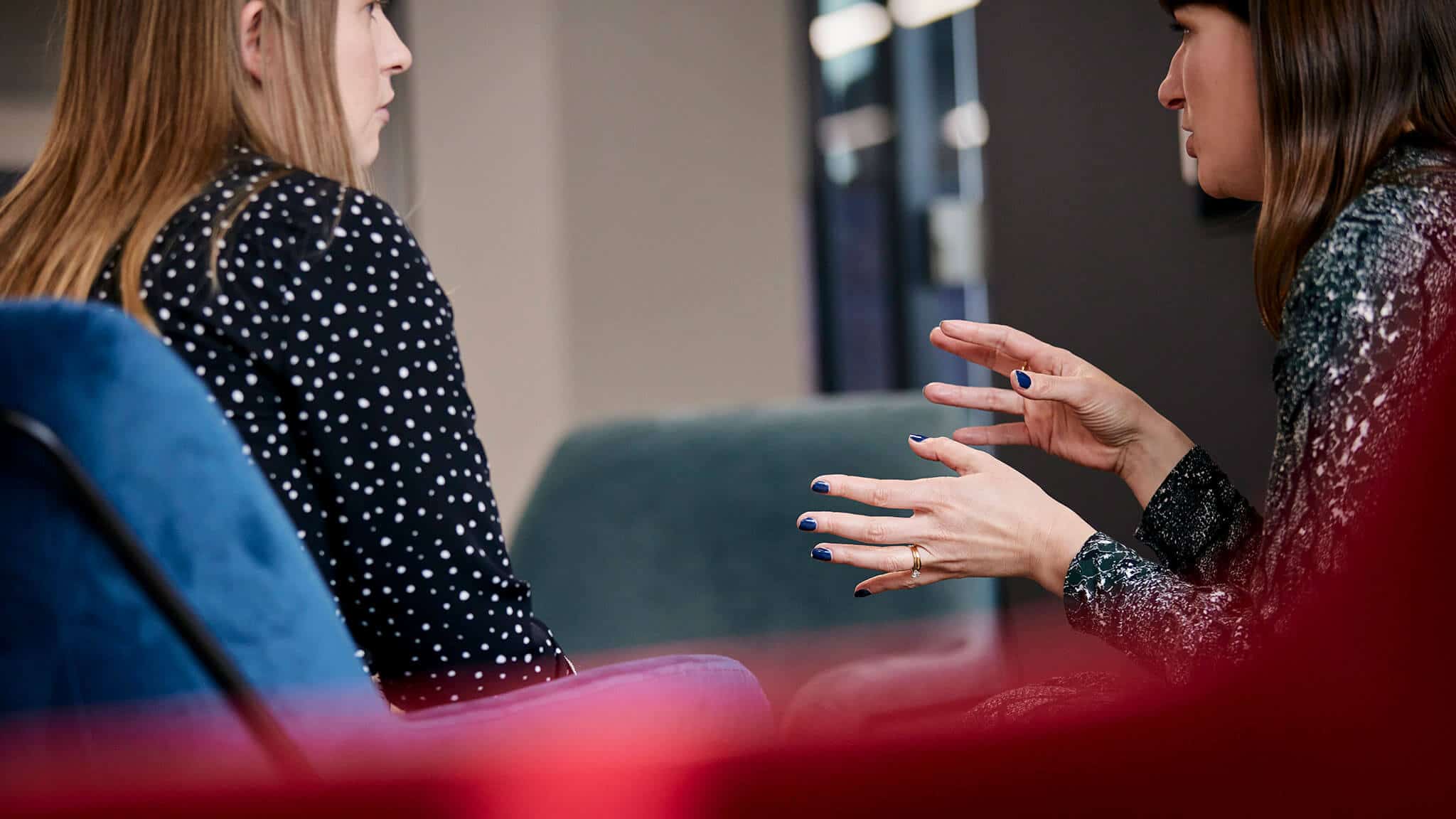 Two women in conversation, one gesturing with both hands