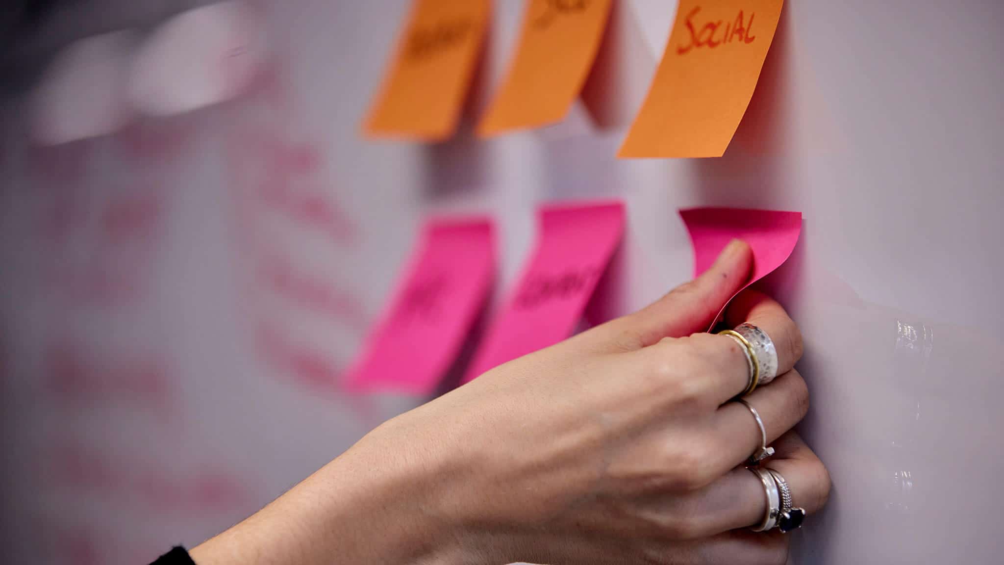 Close up shot of hand putting post-it notes on a whiteboard