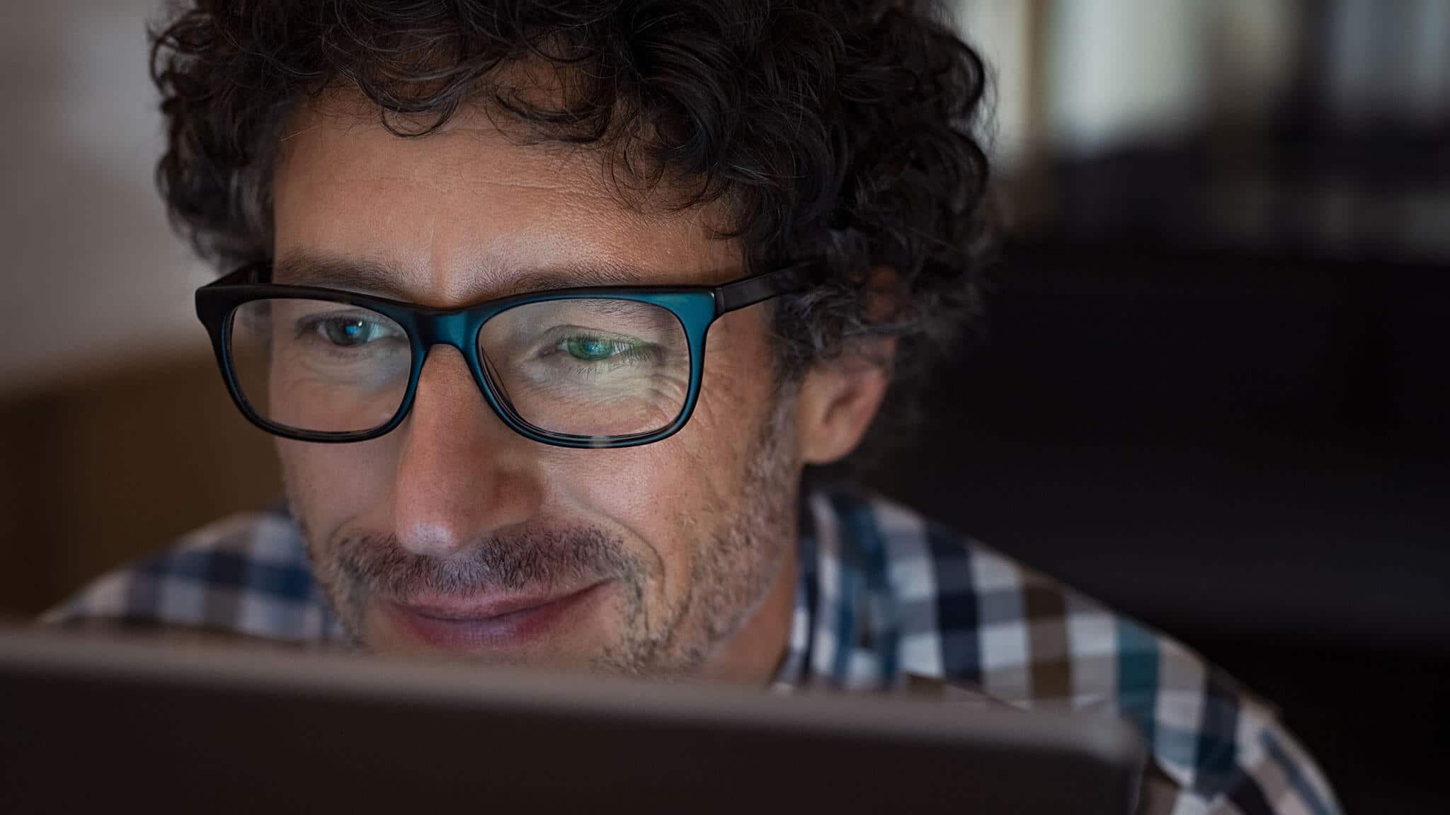 Close up of man with thick curly hair and black framed glasses