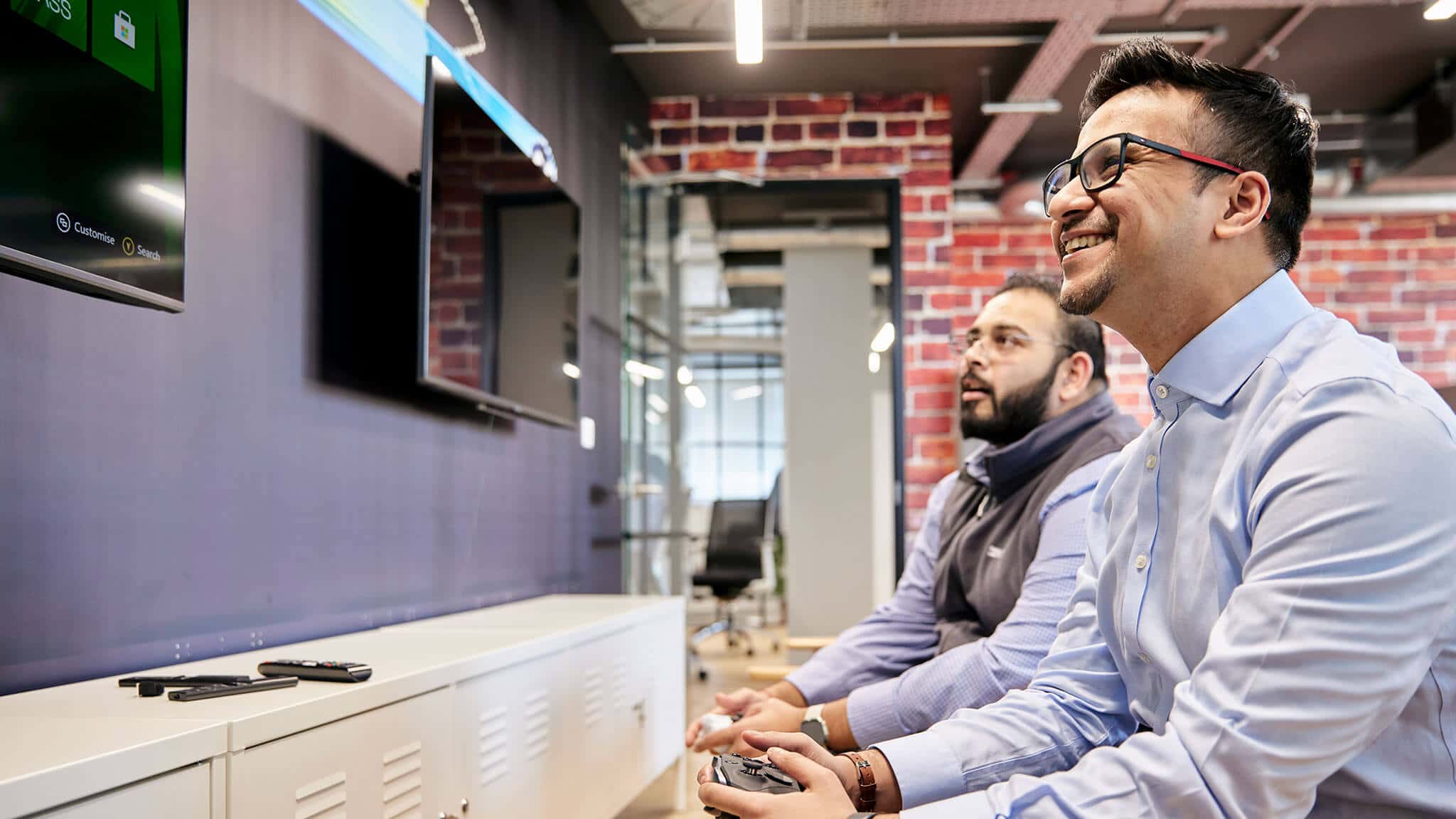 Two men sat down smiling and gaming