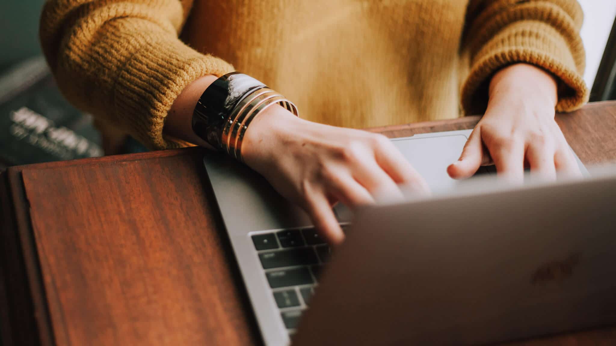 Close up of hands typing on laptop partially obscured by screen