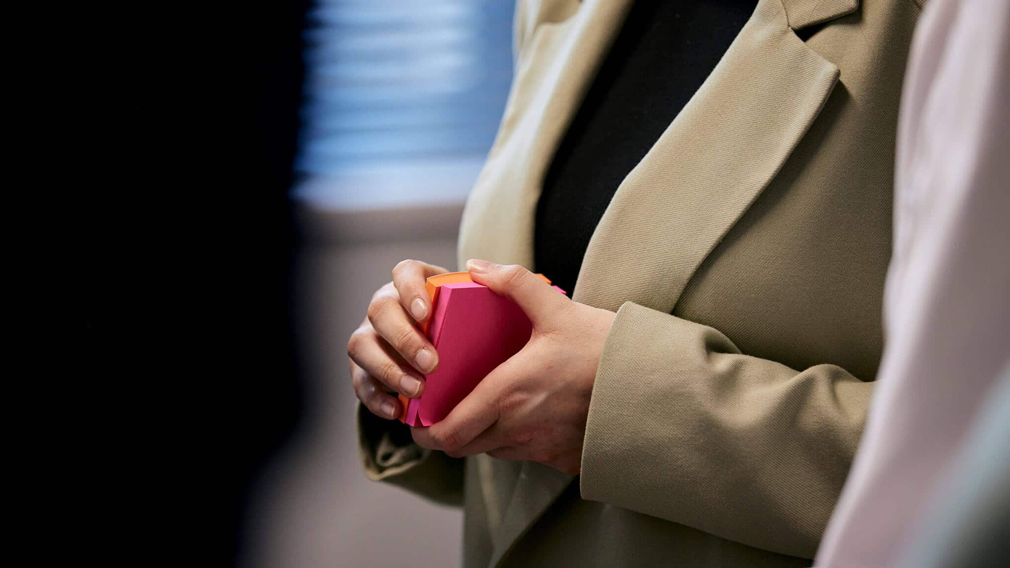 Close up of hands holding orange and pink post-it notes