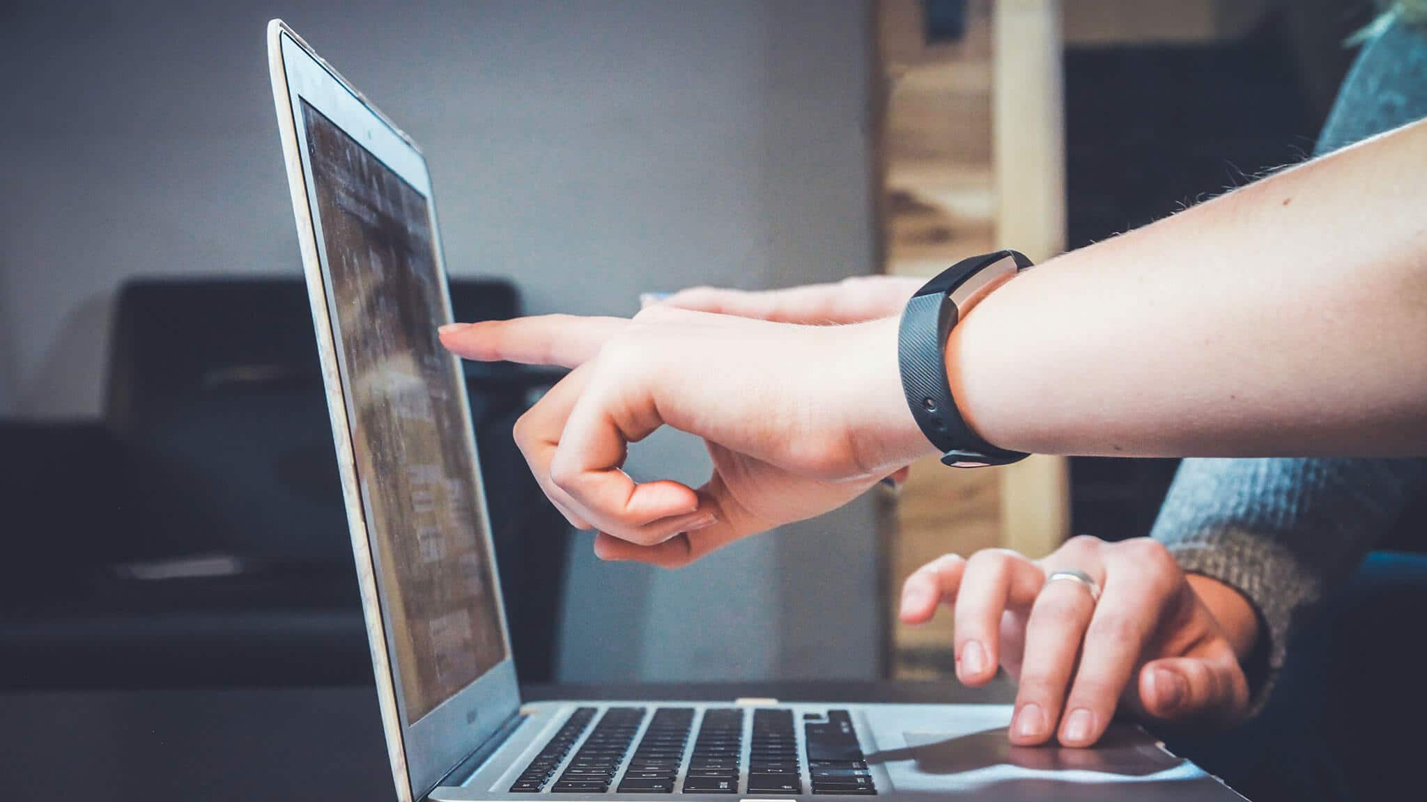 Two hands pointing at laptop screen