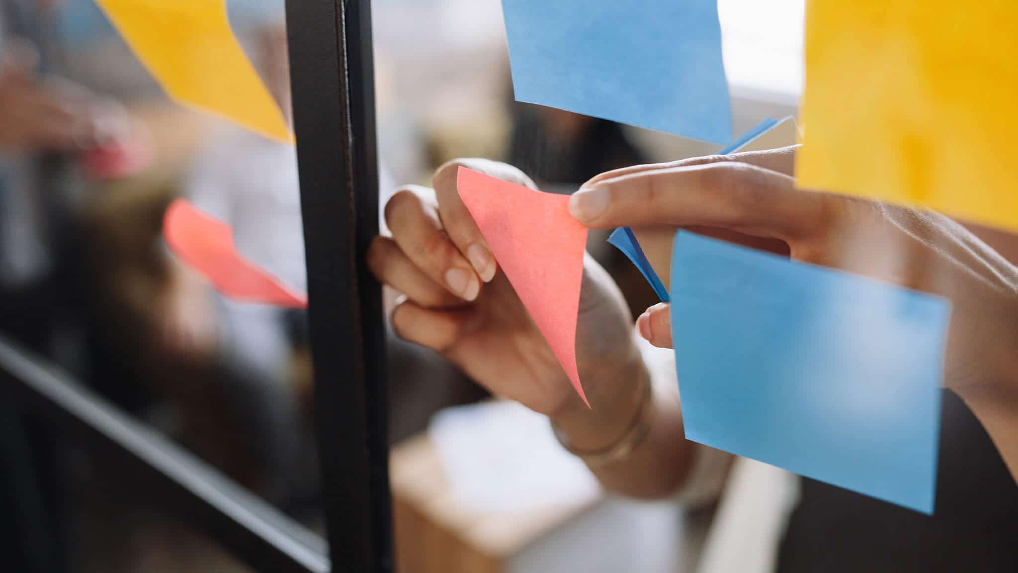 Close up of women&#039;s hands placing post-it notes on glass