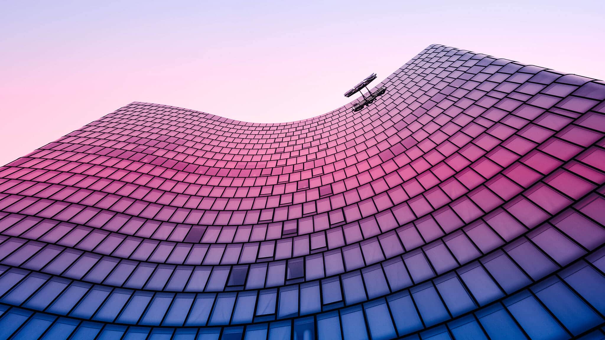 Low angle shot of building with pink and purple curved glass front