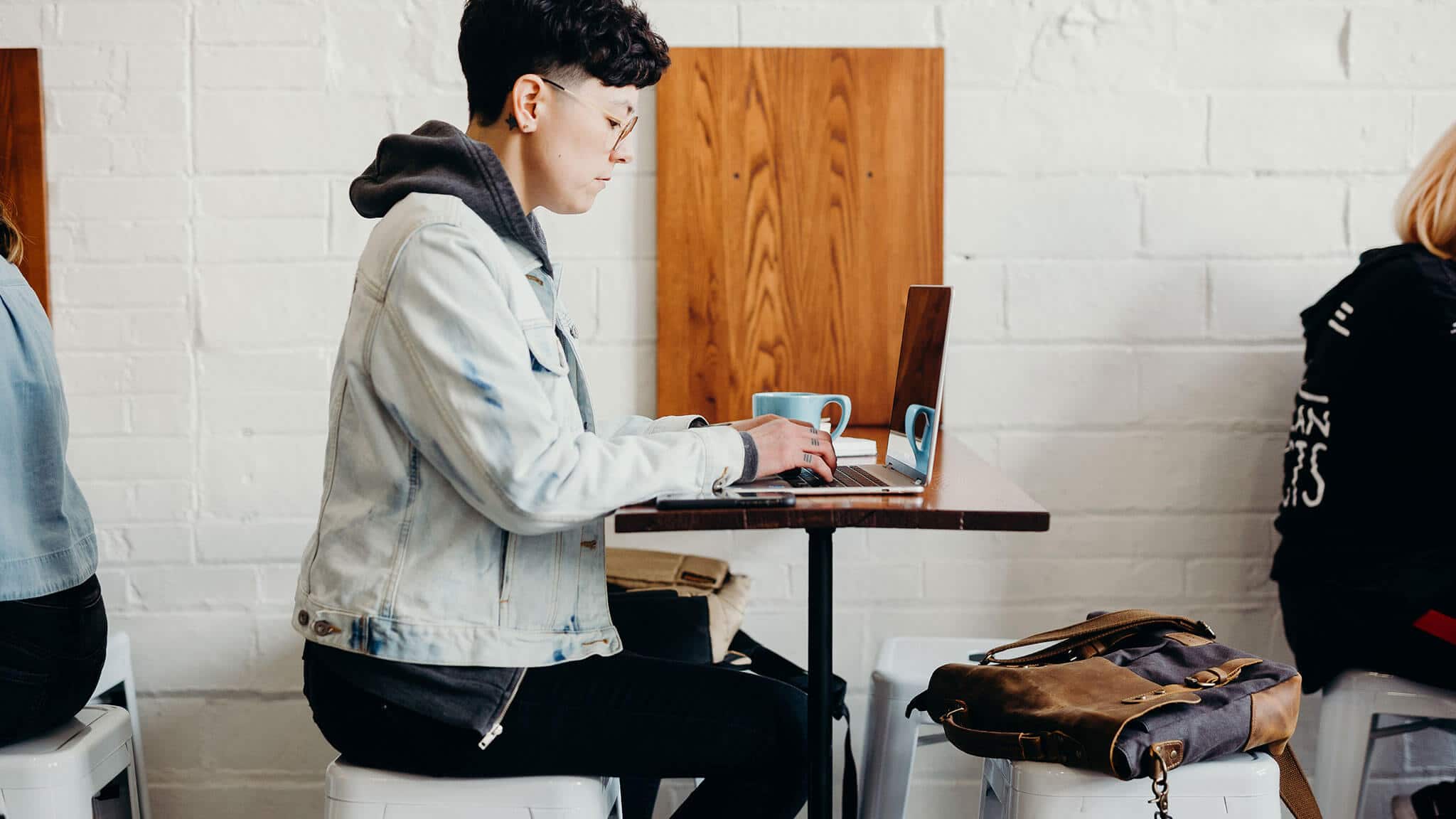 Wide angle shot of person sat at a table using laptop in a cafe