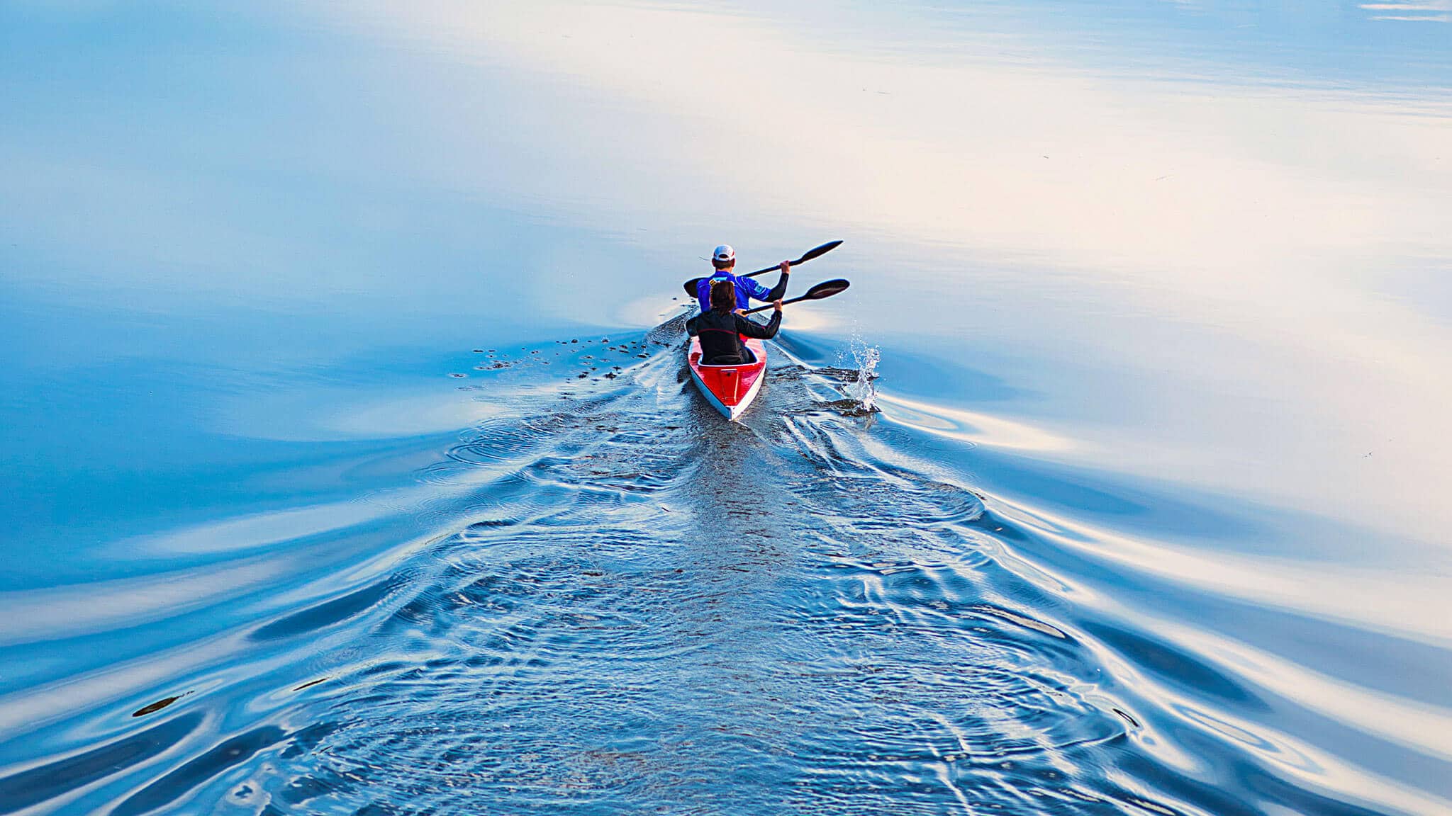 Wide angle shot of two people in canoe paddling away