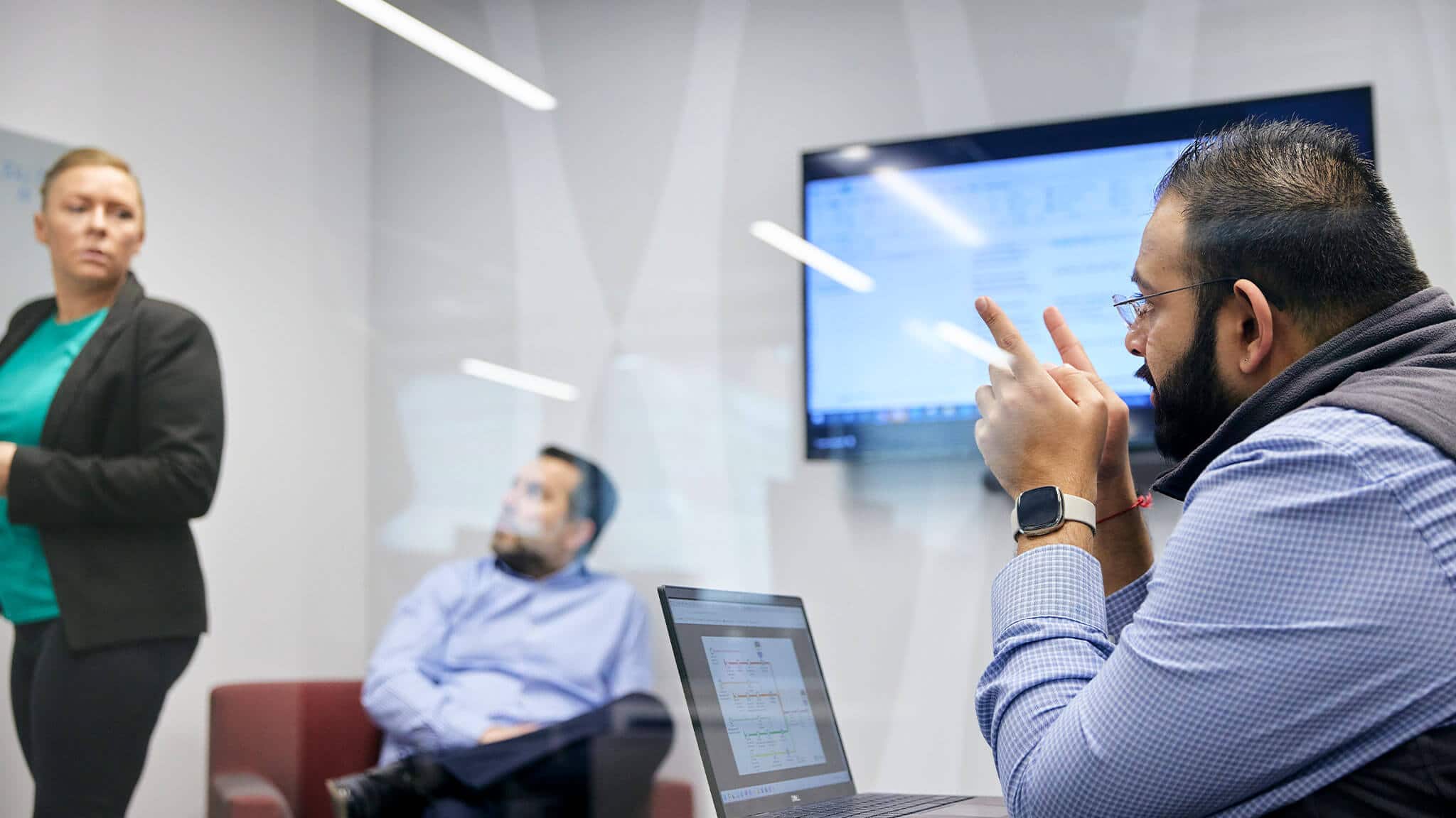 Close up of bearded man in blue check shirt behind laptop