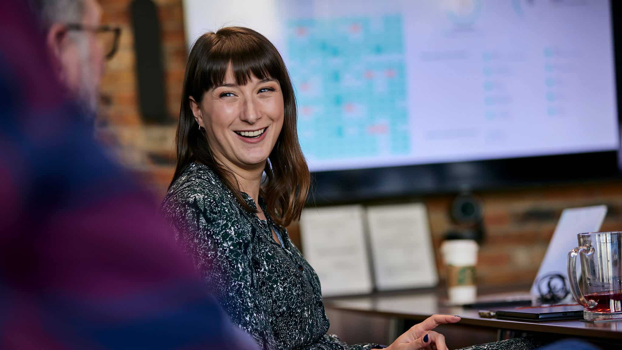 Woman looking at man and laughing in a boardroom.